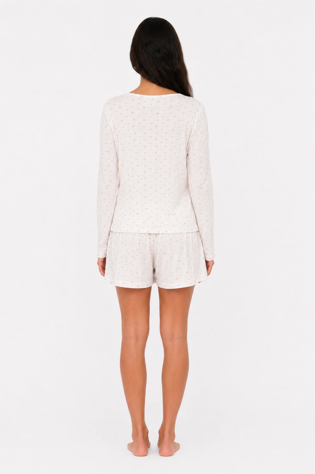 Person wearing a white long-sleeve top and shorts set on a white background