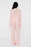 Person wearing a light pink pajama set on a white background