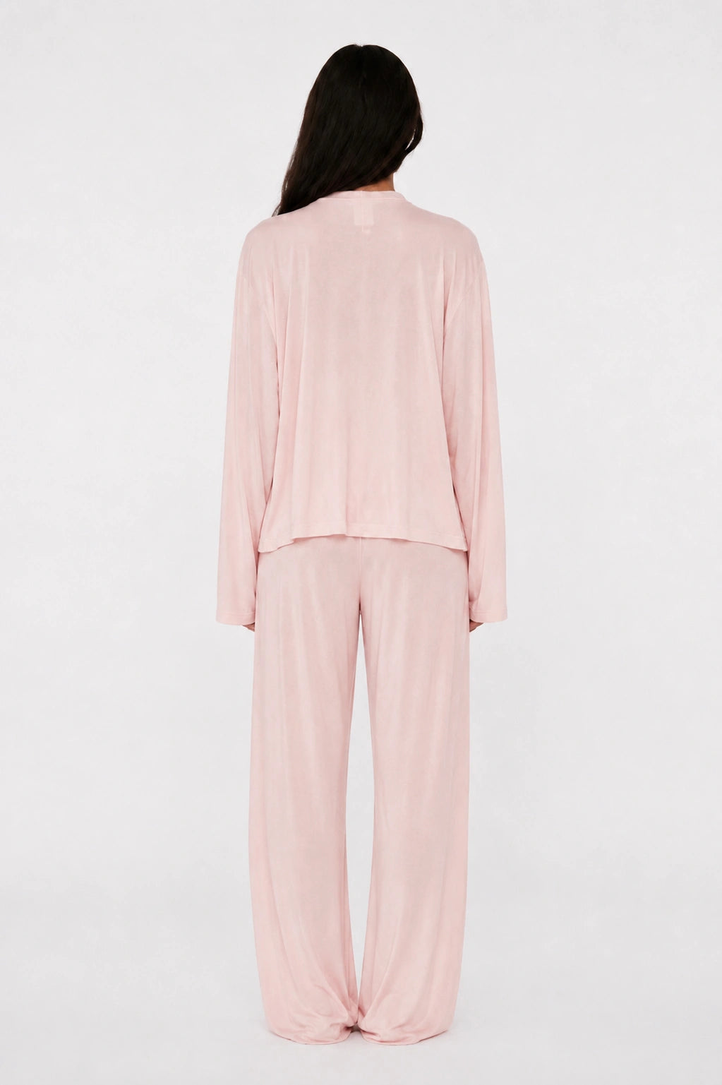 Person wearing a light pink pajama set on a white background