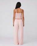 Woman wearing a pink outfit with wide-leg pants on a white background