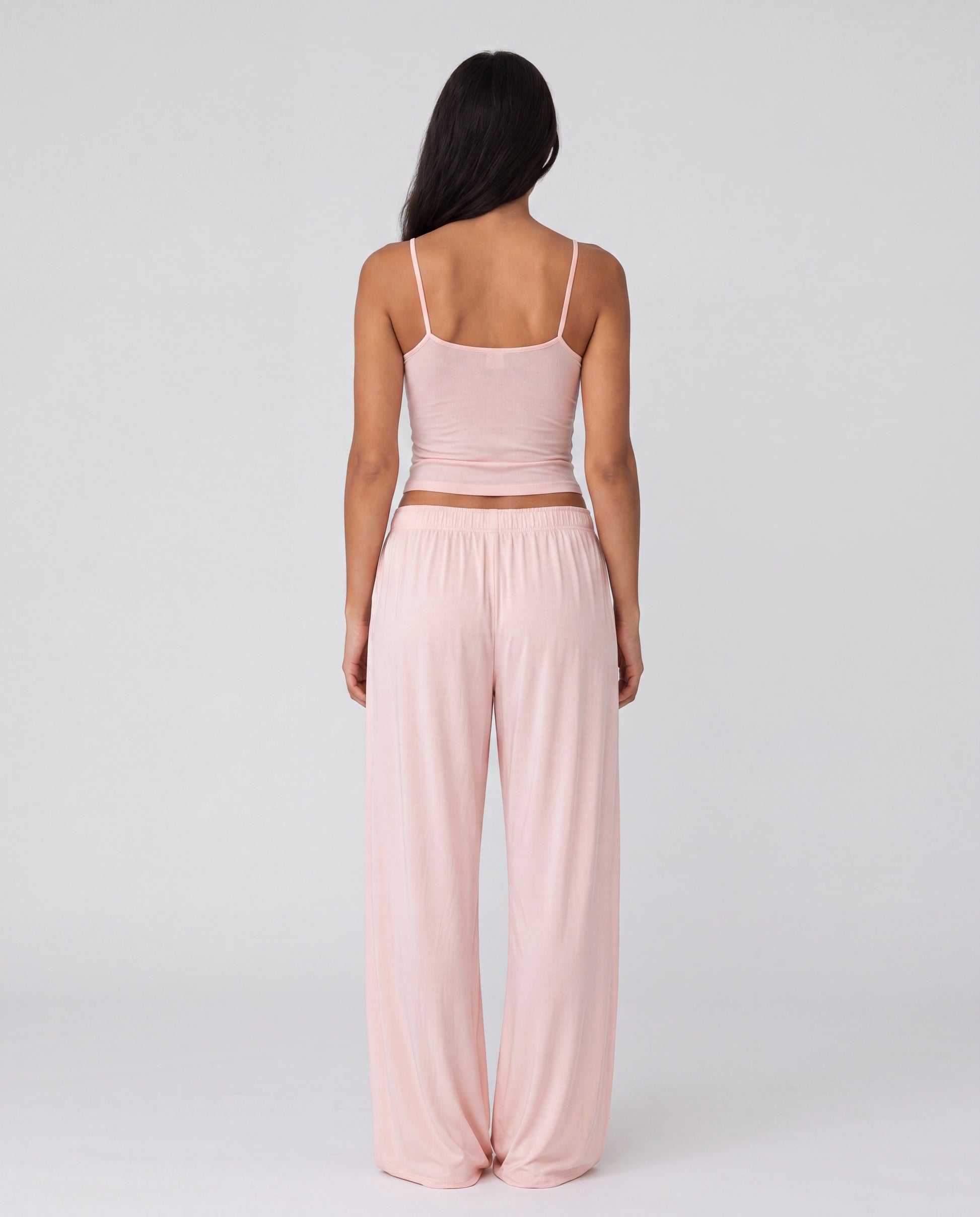 Woman wearing a pink outfit with wide-leg pants on a white background