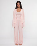 Woman wearing a pink outfit with a matching cardigan on a white background