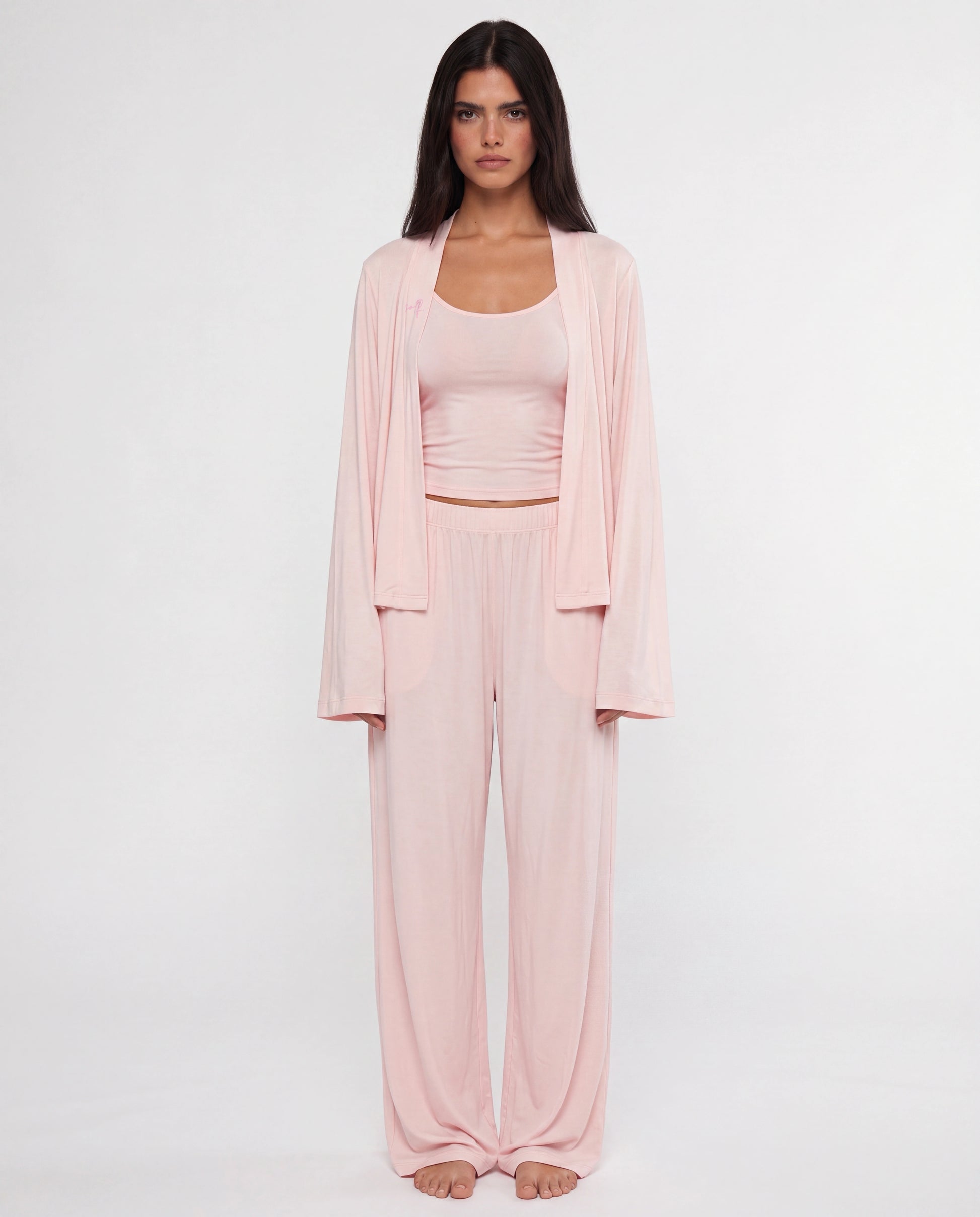 Woman wearing a pink outfit with a matching cardigan on a white background
