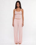 Woman wearing a pink tank top and pants on a white background