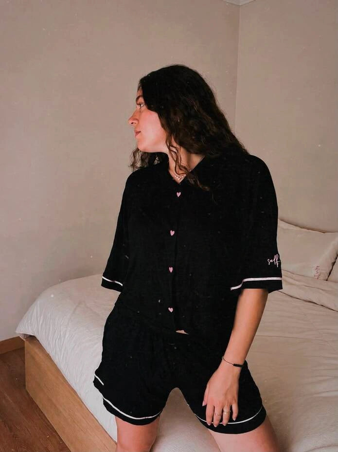 Woman wearing a black pajama set with white trim on a white background