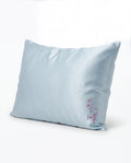 Light blue pillow with 'self' embroidery on a white background
