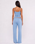 A woman shown from the back wearing a light blue two-piece lounge set consisting of a spaghetti-strap crop top and matching wide-leg pants, set against a plain white studio background.
