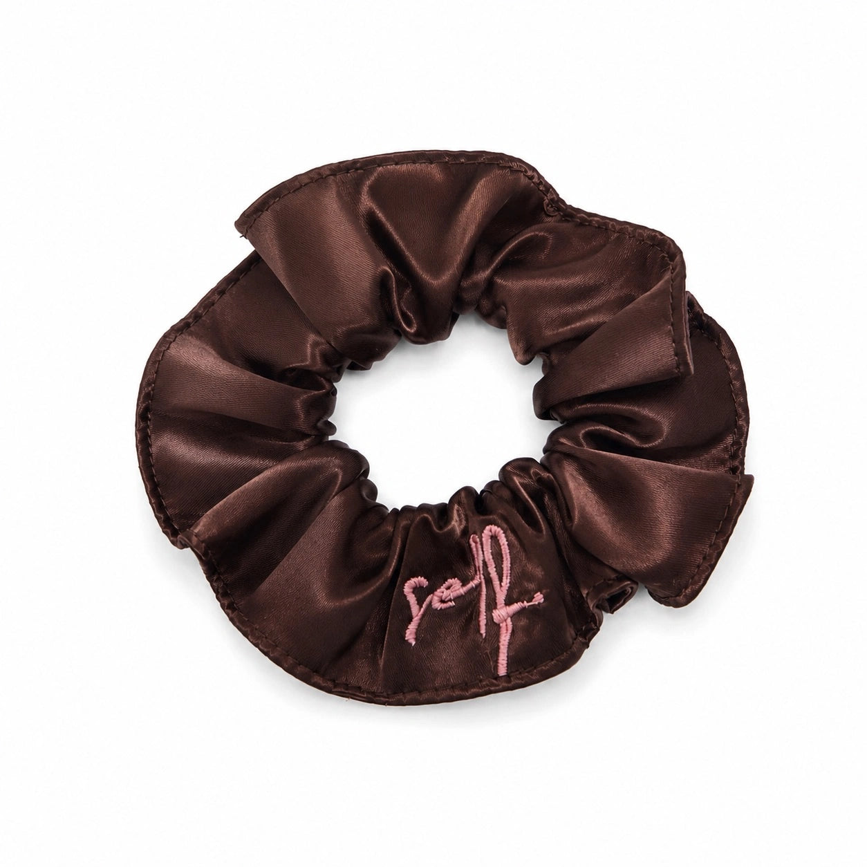 A dark brown satin hair scrunchie with a pink embroidered script logo on the front, displayed on a clean white background.