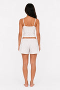 Woman wearing a white floral tank top and shorts set on a white background