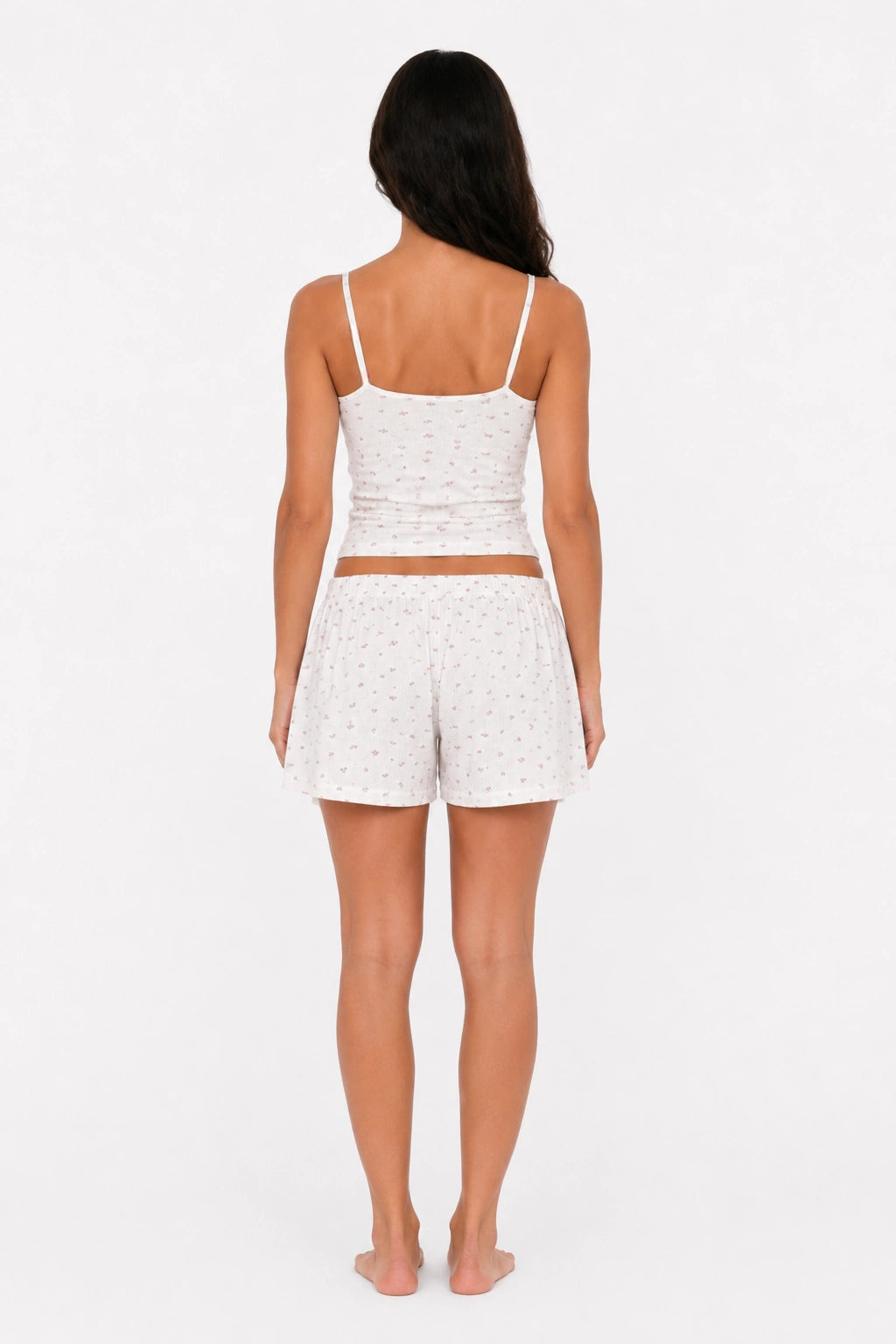 Woman wearing a white floral tank top and shorts set on a white background