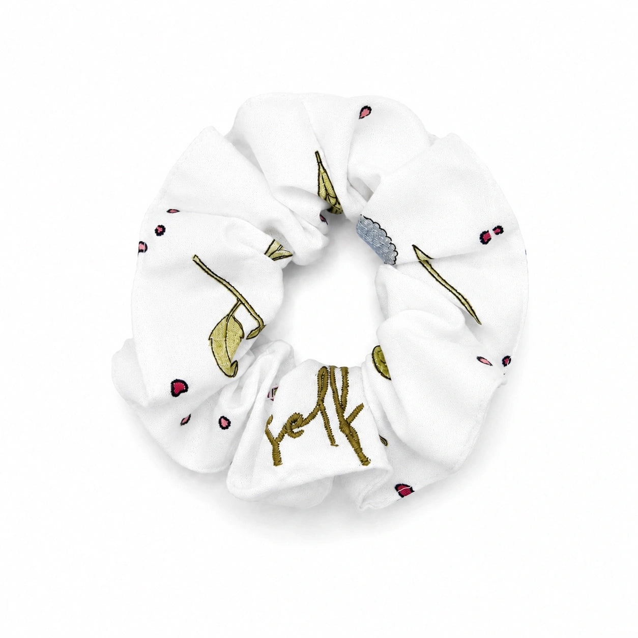 A white fabric scrunchie featuring a delicate gold and green botanical pattern with small red berry accents, shown against a plain white background.