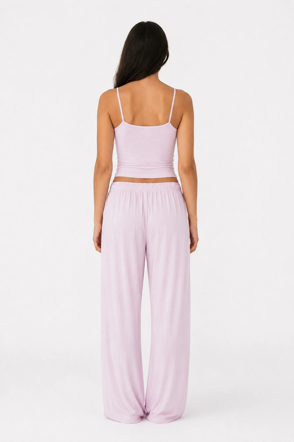 Woman wearing a lilac top and wide-leg pants on a white background