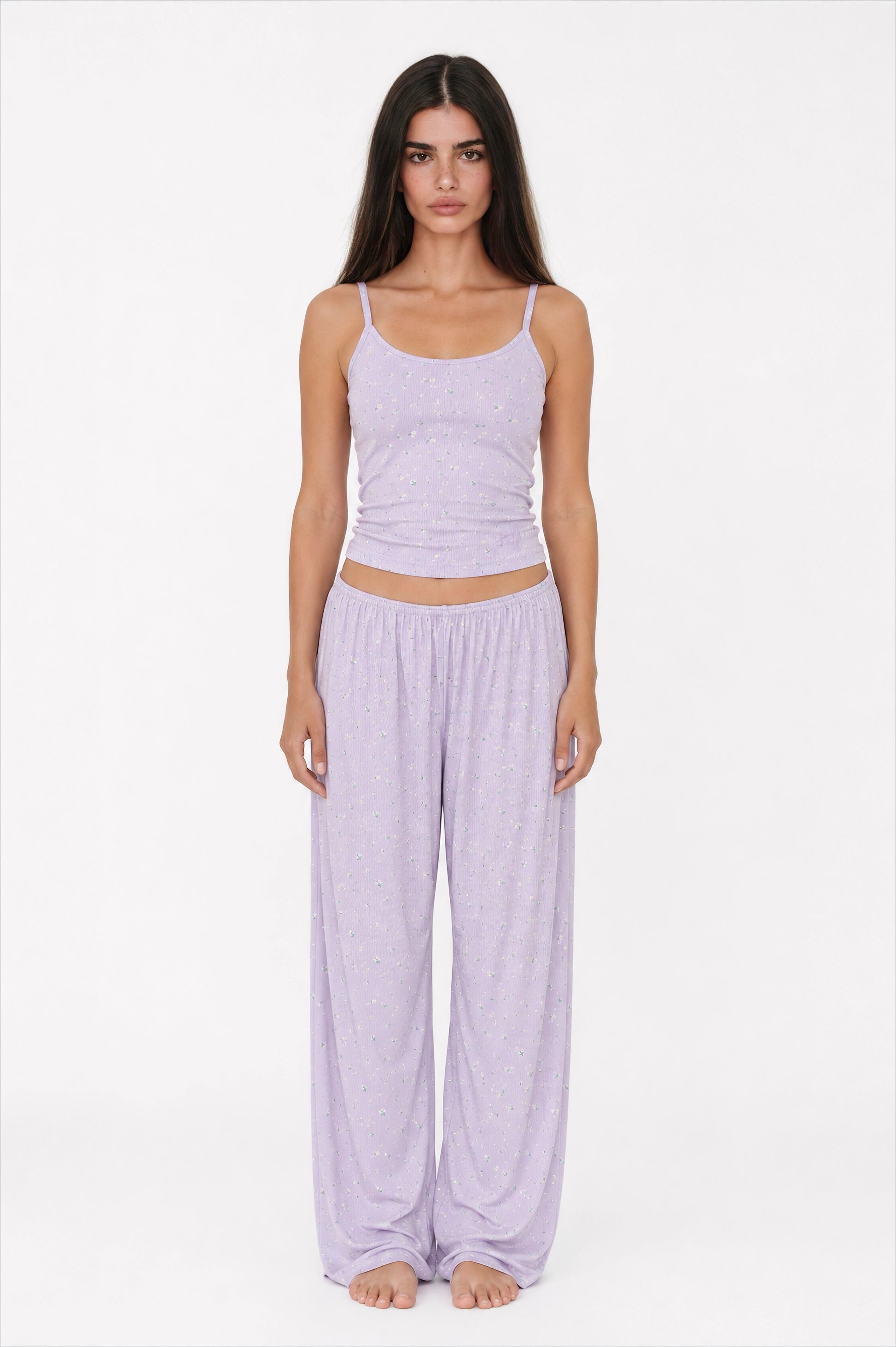 Woman wearing a light purple tank top and wide-leg pants on a white background