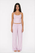 Woman wearing a lilac tank top and wide-leg pants on a white background
