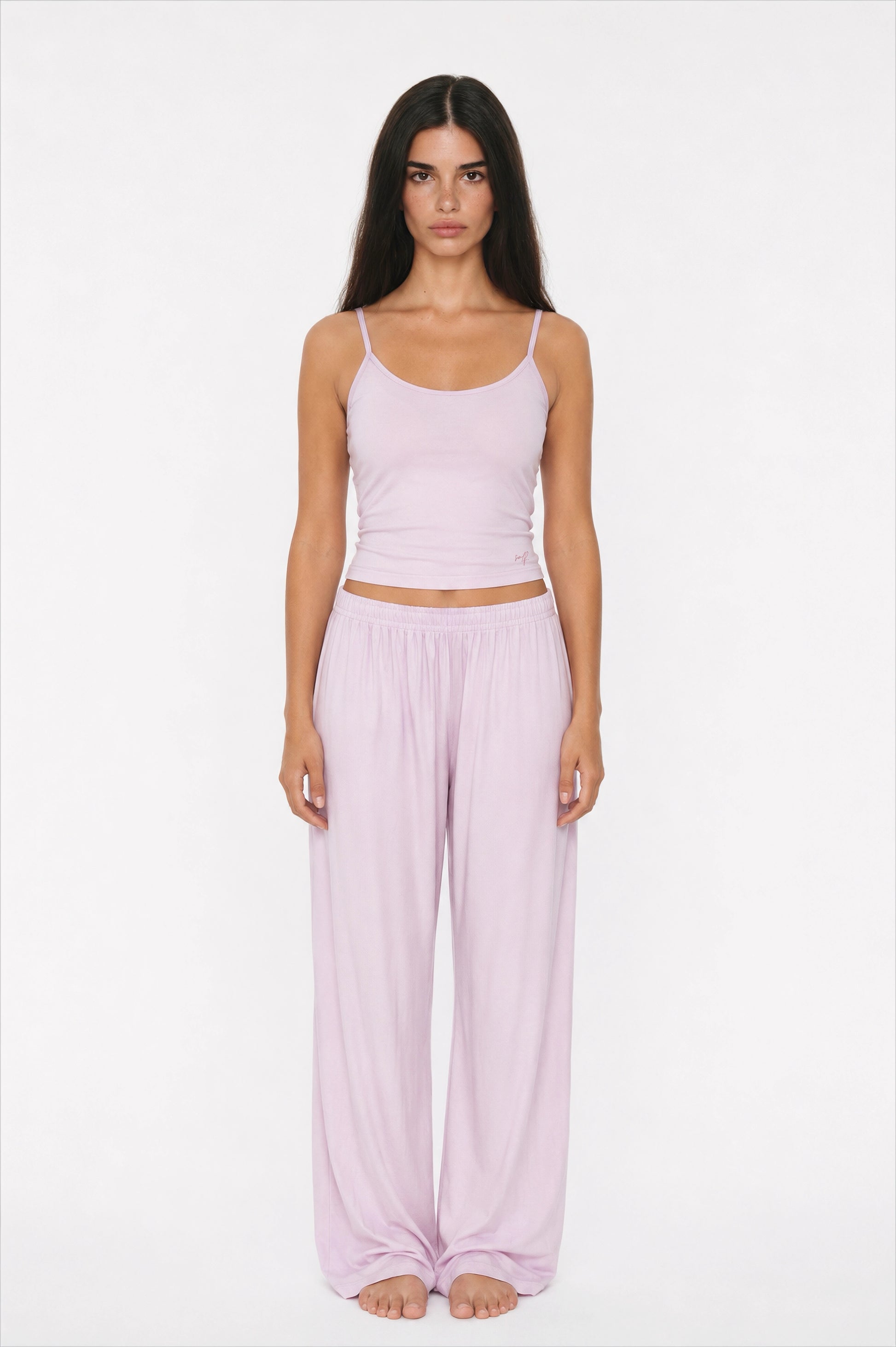 Woman wearing a lilac tank top and wide-leg pants on a white background