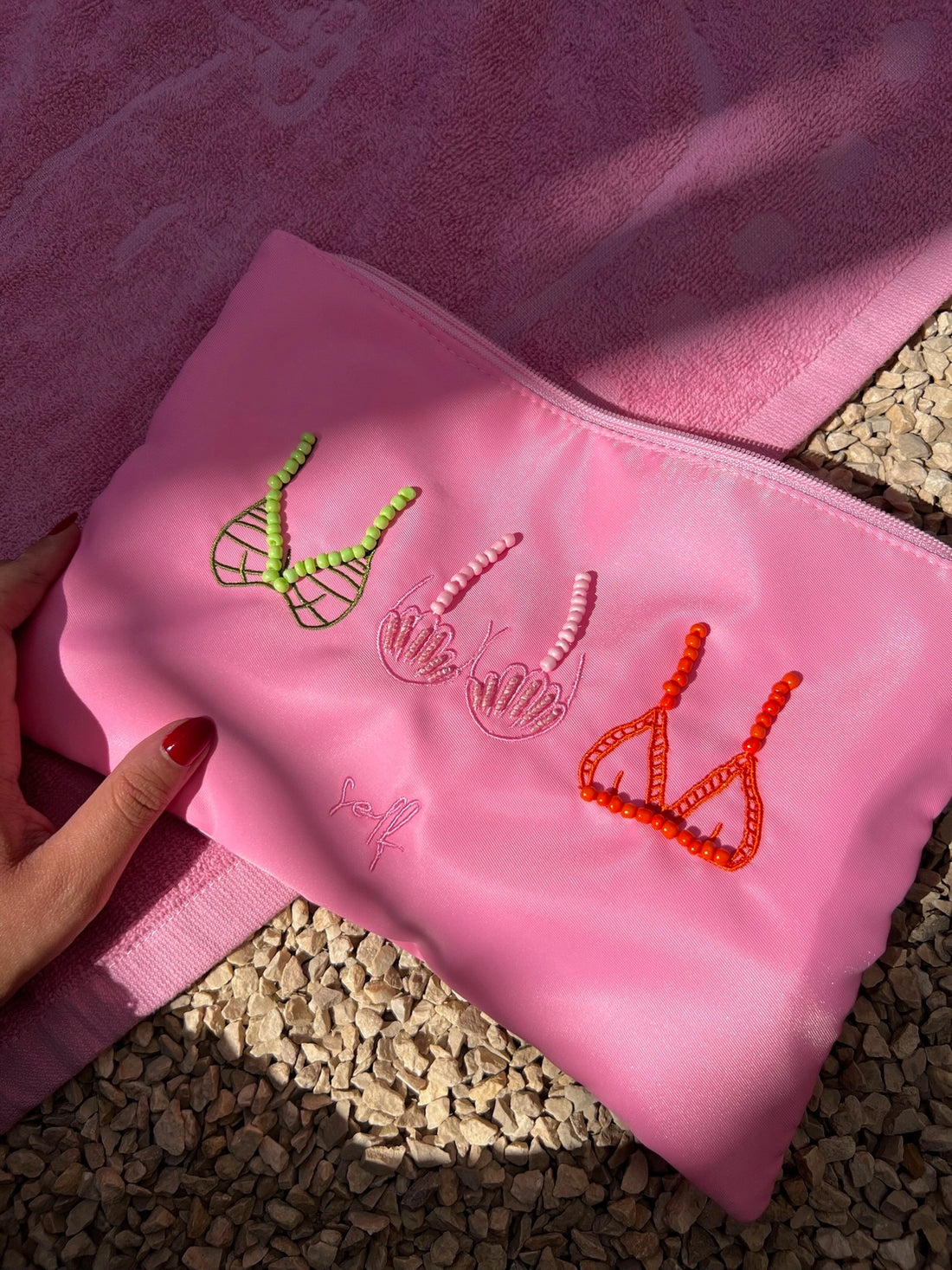 Pink pouch with embroidered designs on a textured surface