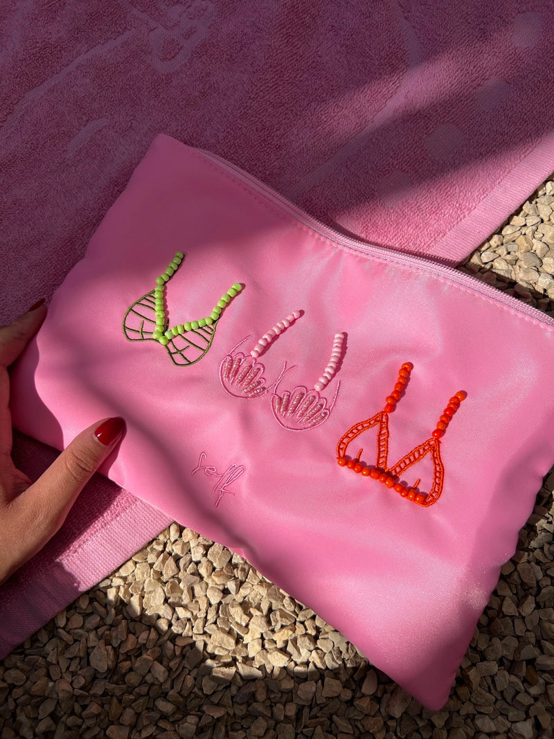 Pink pouch with embroidered designs on a textured surface