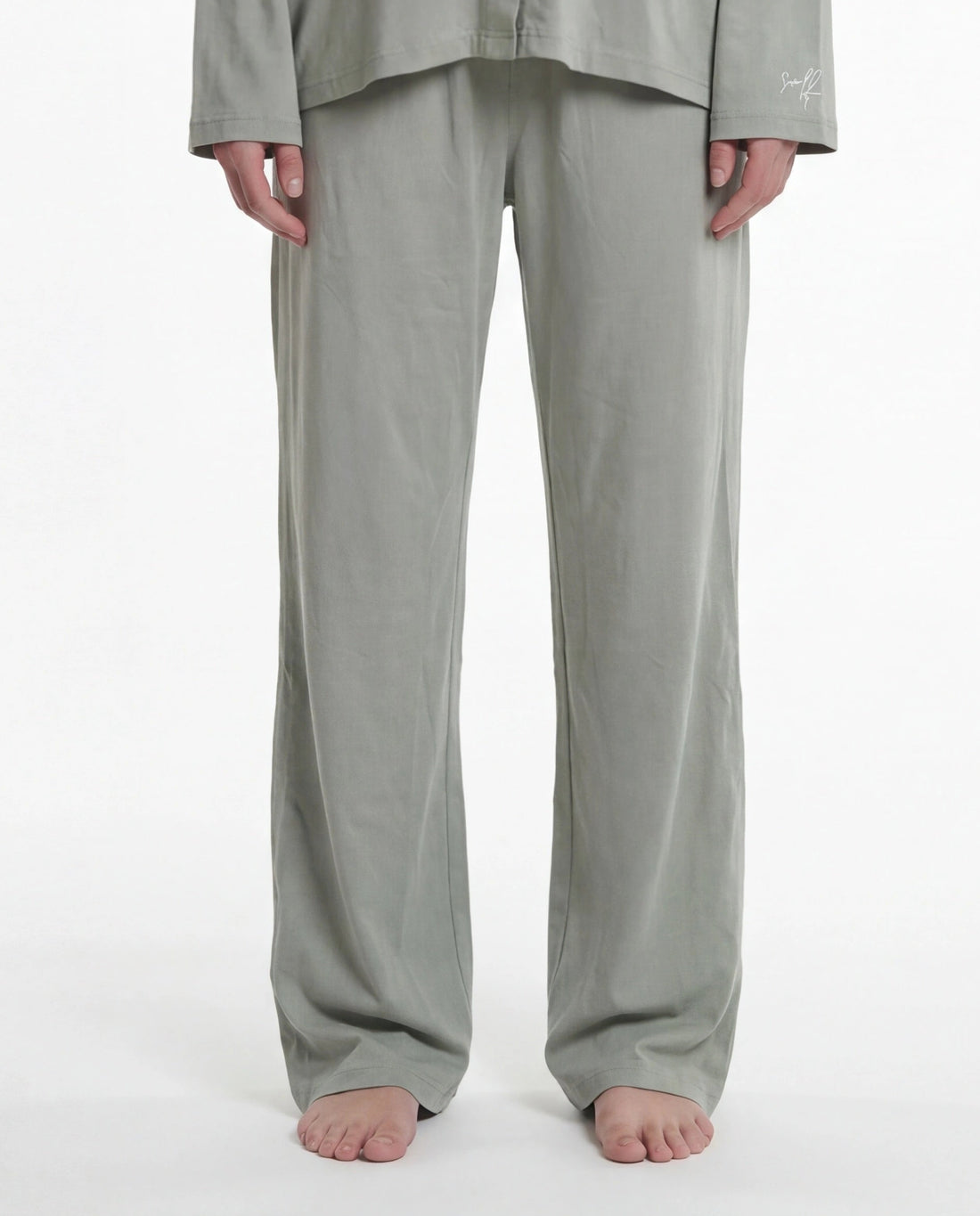 Woman wearing a light sage pajama set on a white background