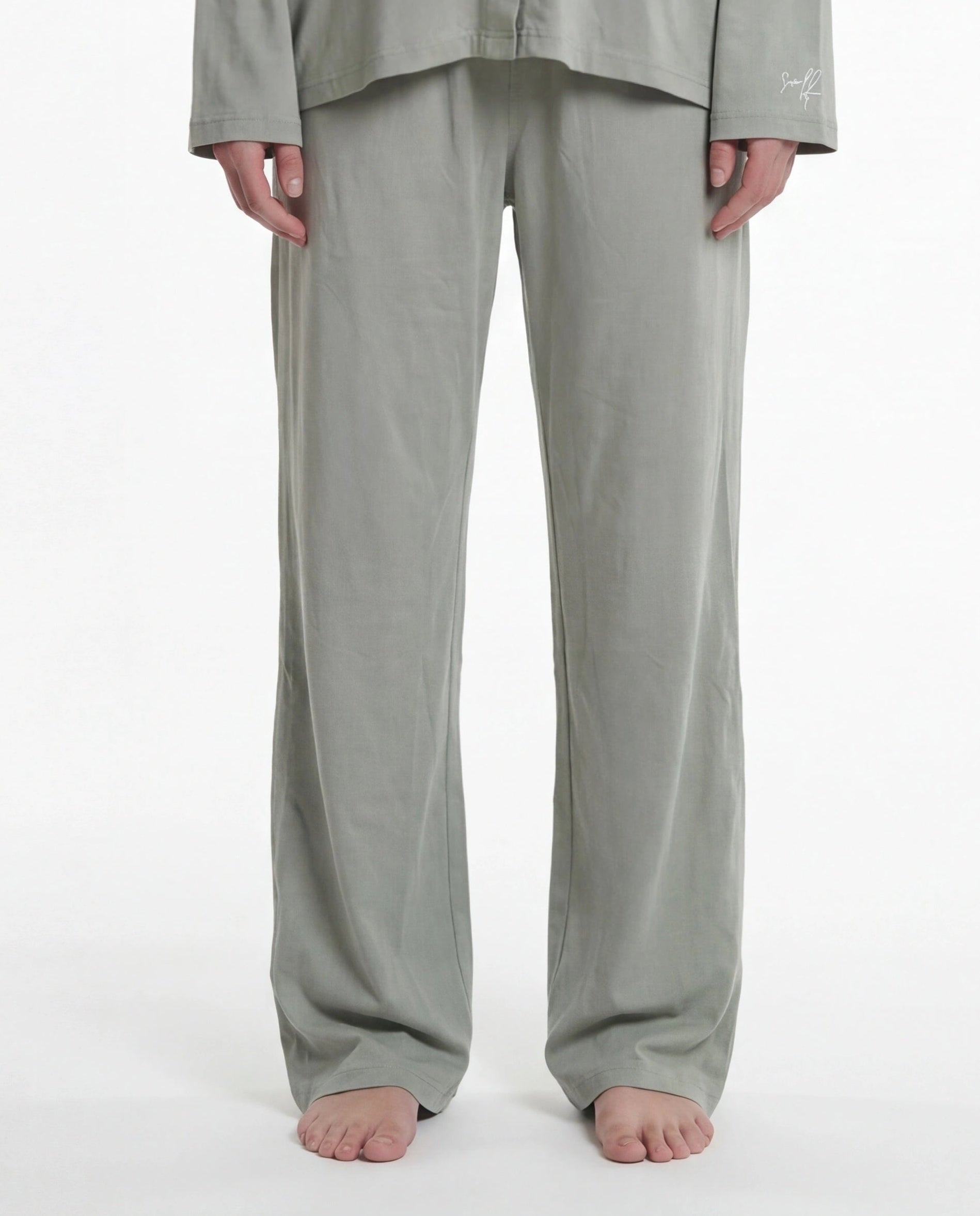 Woman wearing a light sage pajama set on a white background