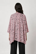 Person wearing a pink patterned shirt with black pants on a white background