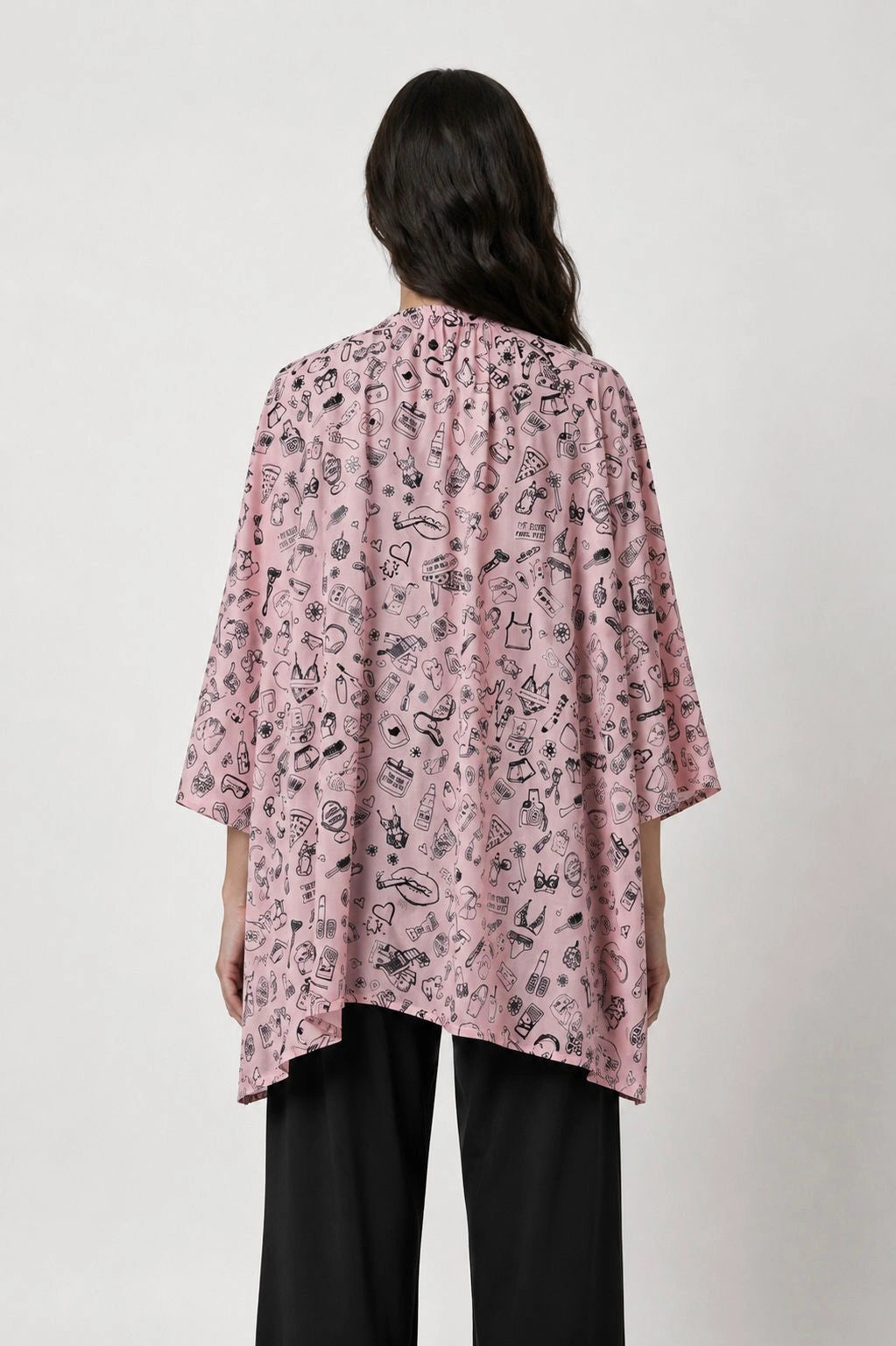Person wearing a pink patterned shirt with black pants on a white background