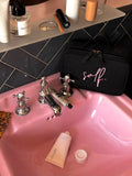 A black zippered cosmetic bag with pink script text reading 'self.' 