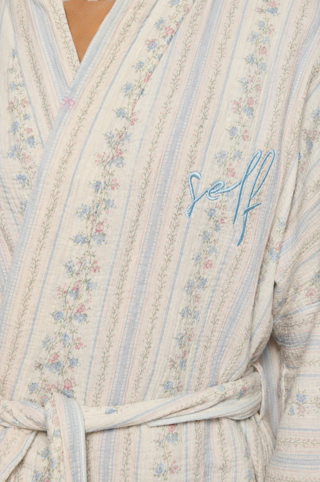 Floral patterned robe with 'Self' embroidery on a wooden background