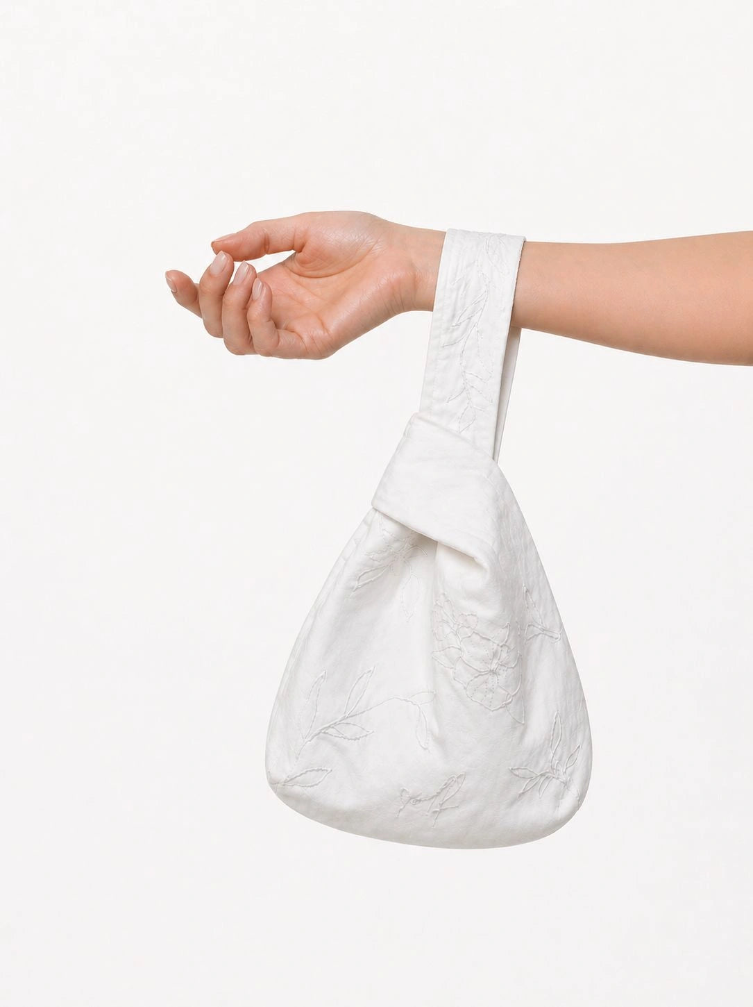 White textured bag held by a hand on a white background