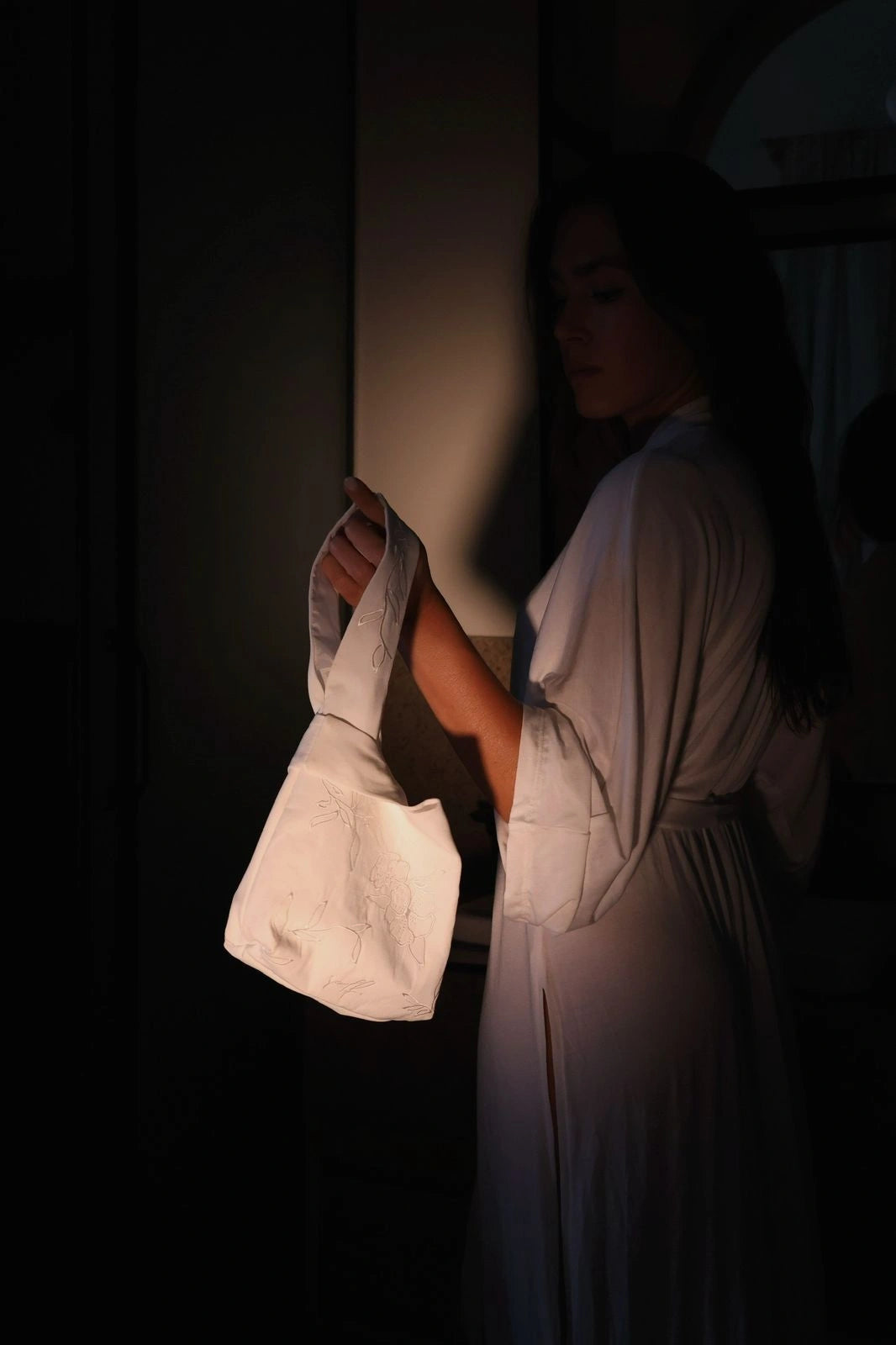Person holding a white bag in a dimly lit room