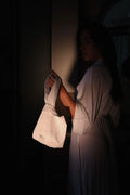 Person holding a white bag in a dimly lit room